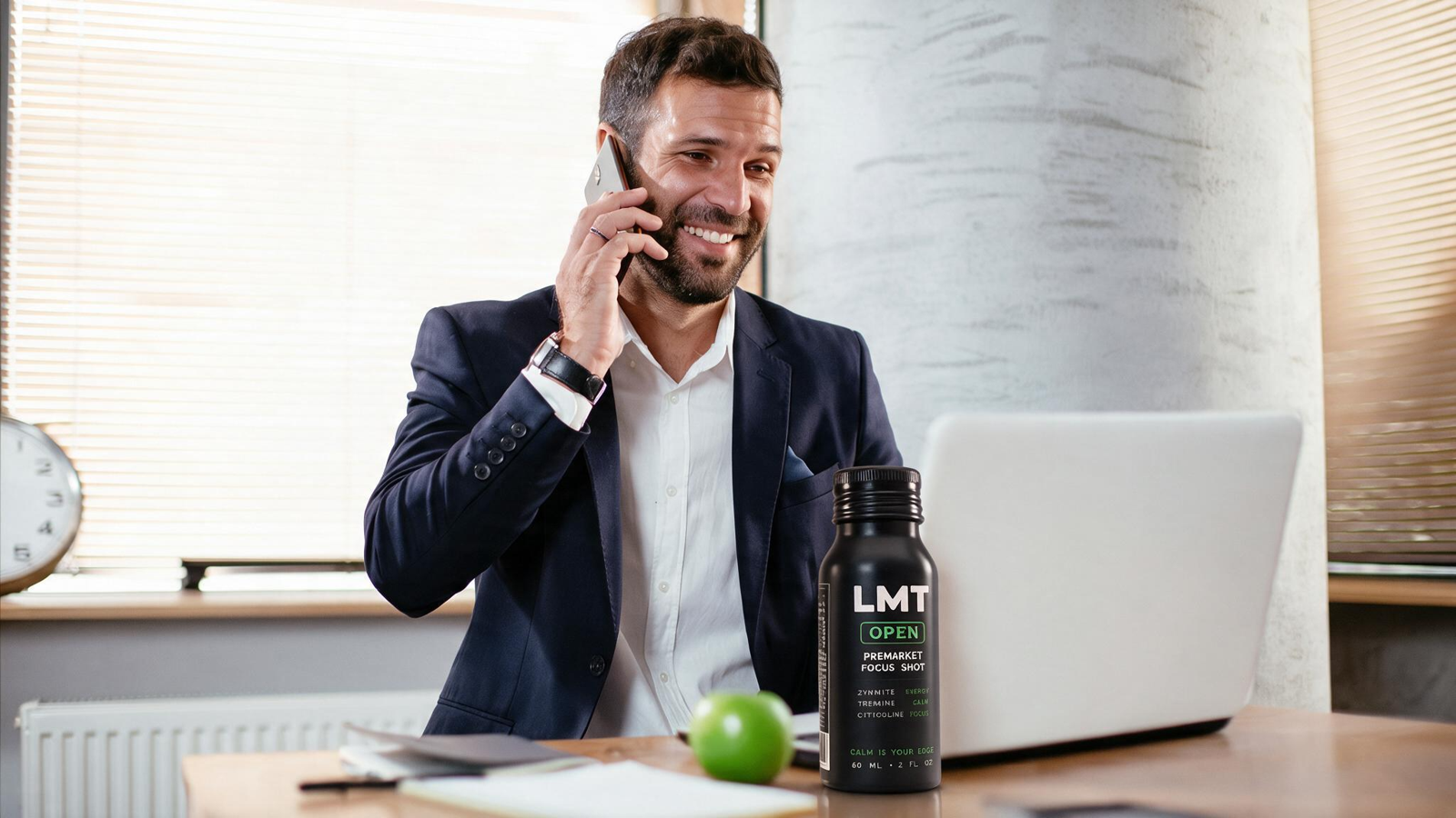 A trader on the phone at a desk with a bottle of LMT Open